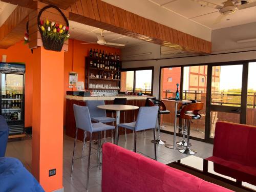 a restaurant with a bar with chairs and tables at AG HOTEL Ouaga in Ouagadougou
