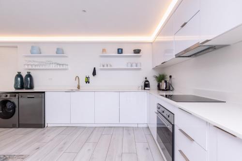 a white kitchen with white cabinets and a dishwasher at MINT Hotel 84 on Katherine in Johannesburg