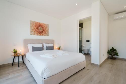 a white bedroom with a large bed and a table at Ammos Villa, beach villa with ocean view in Ribamar
