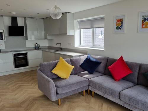 ein Wohnzimmer mit einer Couch mit bunten Kissen darauf in der Unterkunft 16 Cambrian Court - New apartment with stunning sea views in Penmaen-mawr