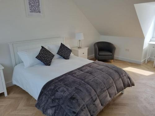 ein Schlafzimmer mit einem großen Bett und einem Stuhl in der Unterkunft 16 Cambrian Court - New apartment with stunning sea views in Penmaen-mawr
