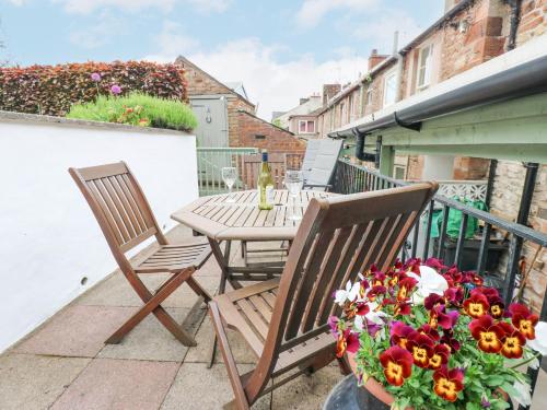 two chairs and a table on a balcony with flowers at Blacksmith Cottage in Appleby
