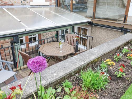 a balcony with a table and chairs and flowers at Blacksmith Cottage in Appleby