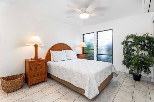 a bedroom with a bed and two night stands and a fan at Sea Village 4108 in Kailua-Kona