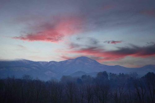 a cloudy sky with mountains in the background and trees at A beautiful sunset cottage in Hendersonville