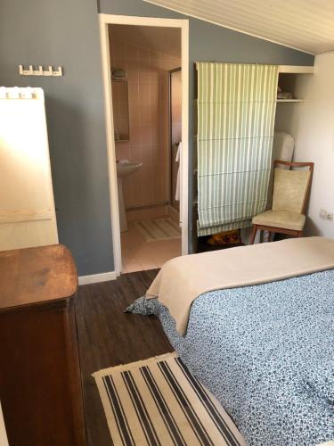 a bedroom with a bed and a chair and a bathroom at le cottage in Apremont