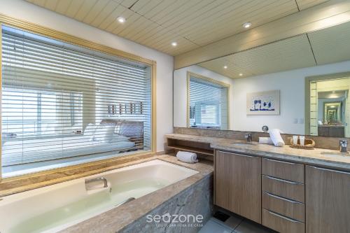 Flat vista mar dentro de resort de luxo STO2206 في فلوريانوبوليس: حمام كبير مع حوض استحمام و نافذة كبيرة
