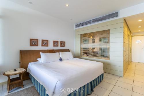 Flat vista mar dentro de resort de luxo STO2206 في فلوريانوبوليس: غرفة نوم بسرير ابيض كبير ونافذة