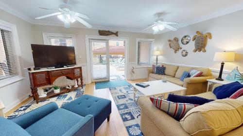 a living room with blue couches and a flat screen tv at Brass Rail Villas 109 by Tybee Vacation Rentals in Tybee Island