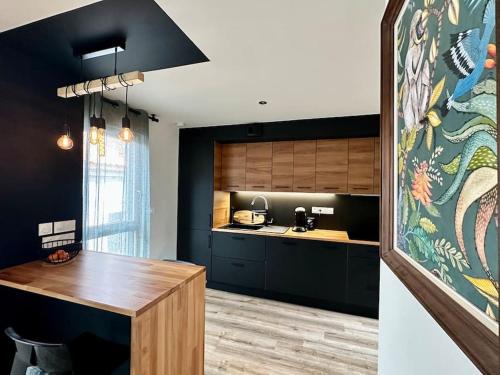 une cuisine avec des armoires noires et une table en bois dans l'établissement L'urbaine, à Le Pellerin