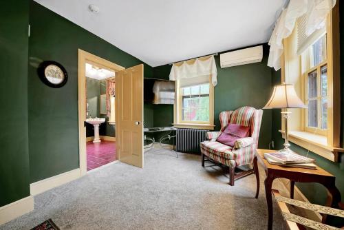 d'un salon avec des murs verts, une chaise et une table. dans l'établissement Cromwell Manor Inn, à Cornwall-on-Hudson
