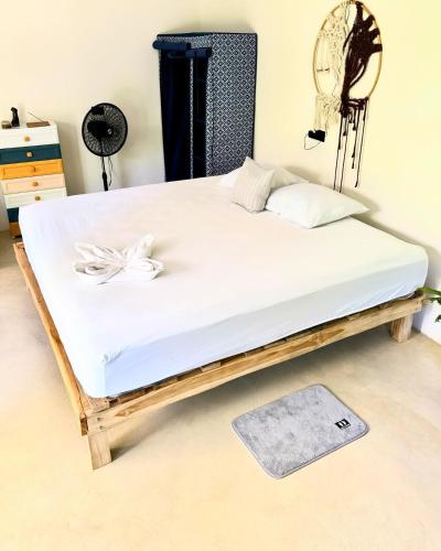 a bed frame with a white mattress and a rug at Deer House Cabuya in Cabuya