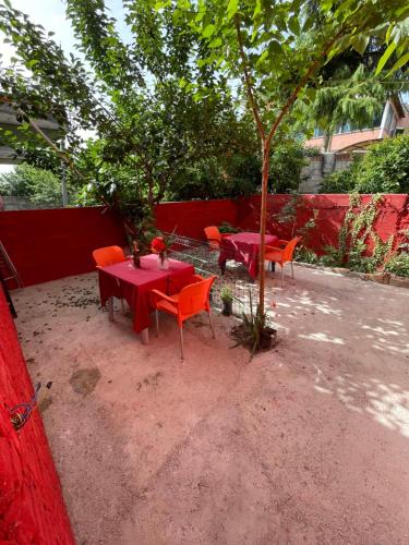 een rode tafel en stoelen en een boom in een tuin bij Hotel Bar Restaurant Mete in Peshkëpi