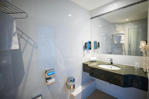 a bathroom with a sink and a mirror at LifeHotel Vienna Airport in Fischamend Dorf