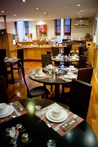 a restaurant with tables and chairs with dishes on them at Hotel Colbert in Saint-Jean-de-Luz