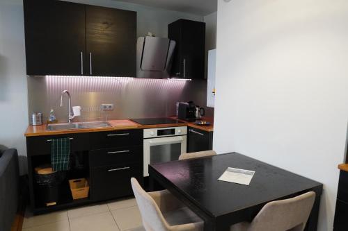 une cuisine avec des armoires noires et une table avec des chaises dans l'établissement Charmant Appartement au Pré, à Le Pré-Saint-Gervais