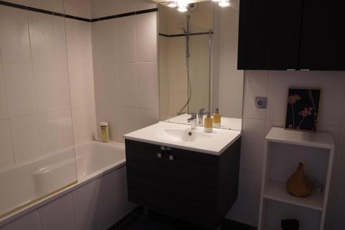 een witte badkamer met een wastafel en een bad bij Charmant Appartement au Pré in Pré Saint Gervais