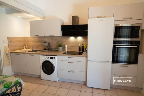 une cuisine avec des armoires blanches et une machine à laver dans l'établissement Villa rénovée climatisée à 500m de la plage, à Vias