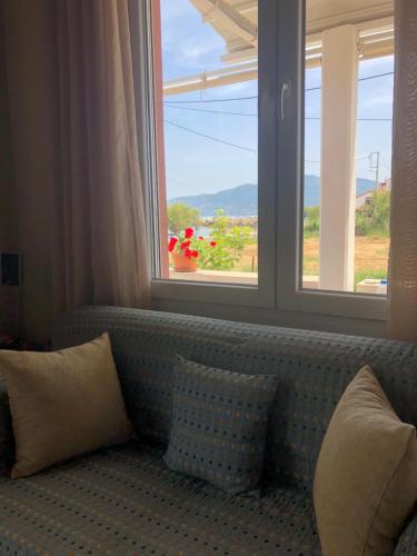 a couch with pillows sitting in front of a window at Modern house by the sea in Apidias Lakos