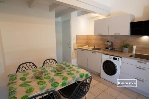une cuisine avec une table et une machine à laver dans l'établissement Villa rénovée climatisée à 500m de la plage, à Vias