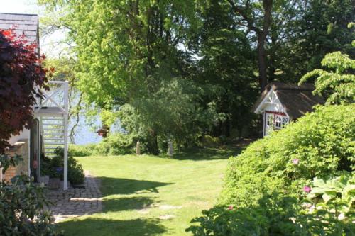a garden with a small house in the background at Ferienhaus direkt am Schmalensee in Schmalensee