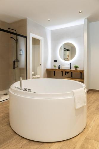 a large white tub in a bathroom with a mirror at Complejo Mirador del Castillo in Alcalá del Júcar