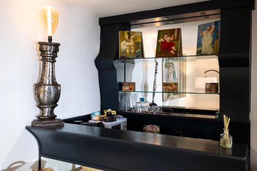 une table noire avec une lampe et des photos sur un mur dans l'établissement La Bravade Luxe et sérénité au cœur de Saint-Tropez Suites spacieuses avec jardin enchanteur, à Saint-Tropez