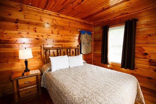 una camera con un letto in una baita di tronchi di The Cabins at Pine Haven - Beckley a Beaver