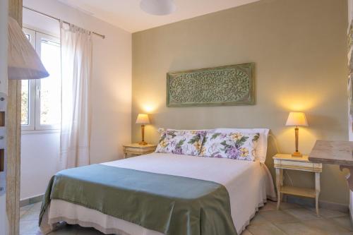 a bedroom with a bed and two lamps and a window at Orosei Home Holidays - Sa Vadde in Cala Liberotto