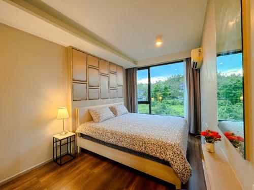 a bedroom with a bed and a large window at Comfy 1 Bedroom Condo in Surin (Seaview Rooftop Pool & Gym) in Phuket Town