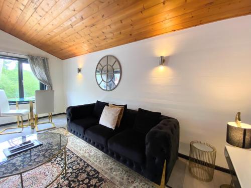 ein Wohnzimmer mit einem schwarzen Sofa und einem Tisch in der Unterkunft Magpie 2 Hot Tub HuntersMoon-Warminster-Longleat-Wiltshire in Warminster