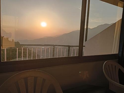 een uitzicht op de zonsondergang vanuit een raam met een stoel bij Amazing view in McLeod Ganj