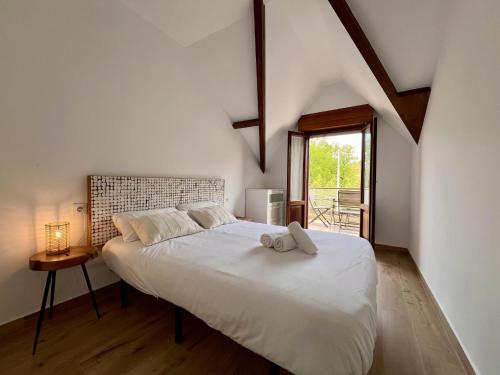 a bedroom with a large white bed with a window at Apartamento La Fuente - Monabri in Somo