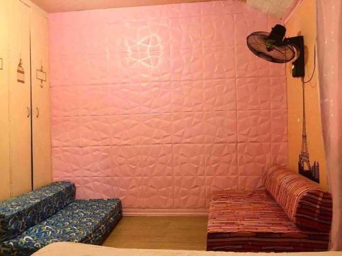 a room with a couch and a pink wall at 7pax, 2 AC BR,Videoke,Games,Netflix,Cook,Parking in Rodriguez