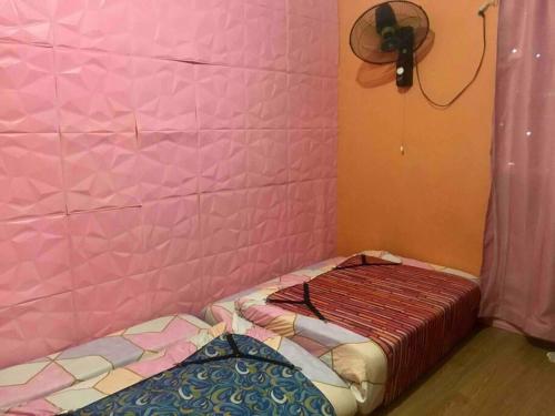 a bed in a room with a pink wall at 7pax, 2 AC BR,Videoke,Games,Netflix,Cook,Parking in Rodriguez