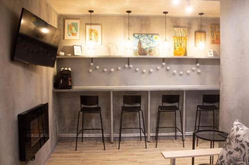 a bar with four stools in a room at City center Artmania apartments in Chişinău