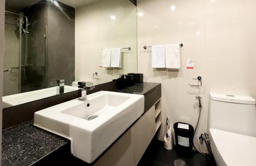 a white bathroom with a sink and a toilet at Comfy 1 Bedroom Condo in Surin (Seaview Rooftop Pool & Gym) in Phuket Town