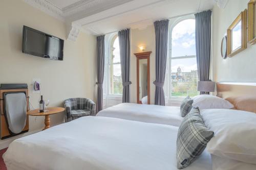 um quarto de hotel com duas camas e uma televisão em Old Waverley Hotel em Edimburgo