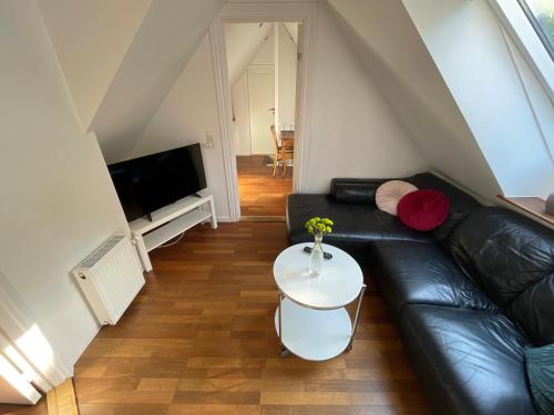 a living room with a black leather couch and a table at Flexsleep&living in Hjortshøj