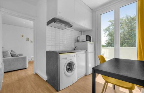 une cuisine avec une machine à laver et une table avec des chaises dans l'établissement Les demoiselles - wifi - parking, à Toulouse