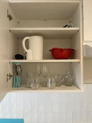 une étagère de cuisine avec des verres et un bol rouge dans l'établissement Le Petit-Beauvoisine, à Rouen