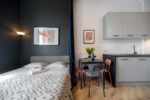 a bedroom with a bed and a table and a kitchen at Art Apartment in Toruń