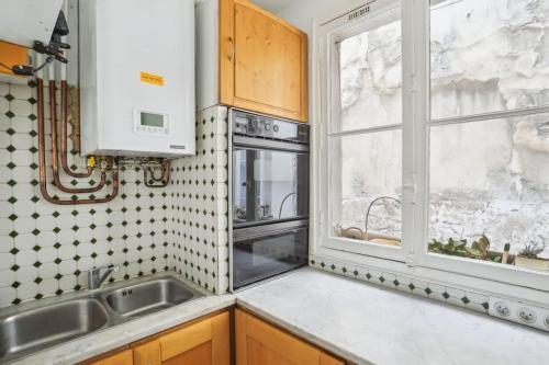une cuisine avec un évier et une fenêtre dans l'établissement L'Atelier du Peintre - Grand Triplex parisien, à Paris