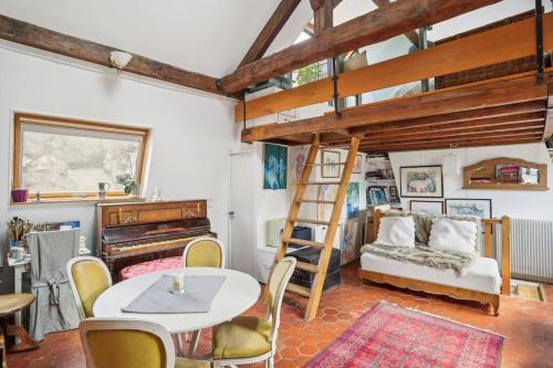 Cette chambre comprend une mezzanine, une table et des chaises. dans l'établissement L'Atelier du Peintre - Grand Triplex parisien, à Paris