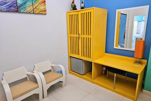 a yellow cabinet with two chairs and a mirror at Phu Jaya Floresta Resort by ALPHATEL PARTNER in Chiang Mai