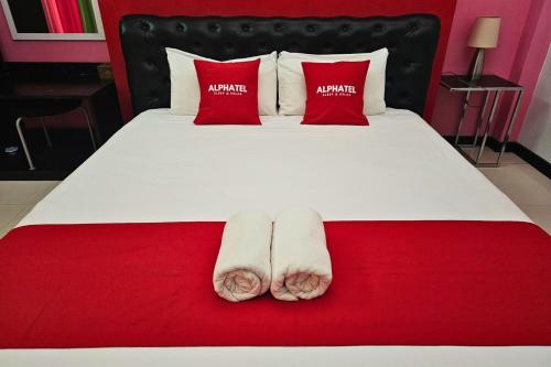 a bed with red pillows and two pairs of slippers at Phu Jaya Floresta Resort by ALPHATEL PARTNER in Chiang Mai