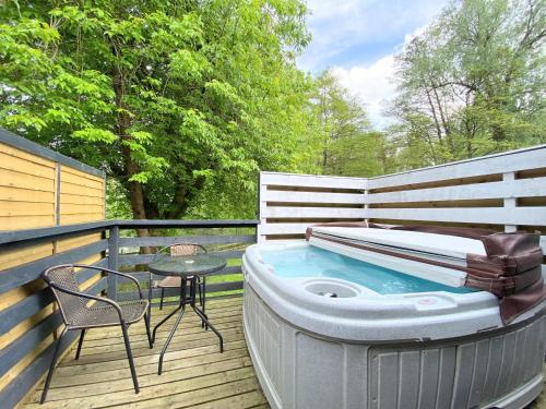 un bain à remous sur une terrasse avec une table et une chaise dans l'établissement Magpie 3 HuntersMoon-Longleat-Warminster-Bath, à Warminster