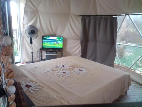 um quarto com uma cama e uma televisão numa tenda em Podere Kiri Dome Experience em Decimomannu