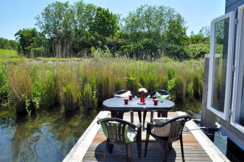 a table and chairs sitting on a deck next to a pond at BestMarine Waterchalets Flevo Marina in Lelystad
