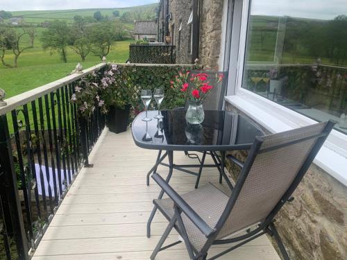 a table and chairs on a balcony with a window at Tilly Cottage - overlooking Pendle Hill in Barrowford